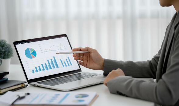 Person analyzing charts on laptop, examining graphs and data statistics photo