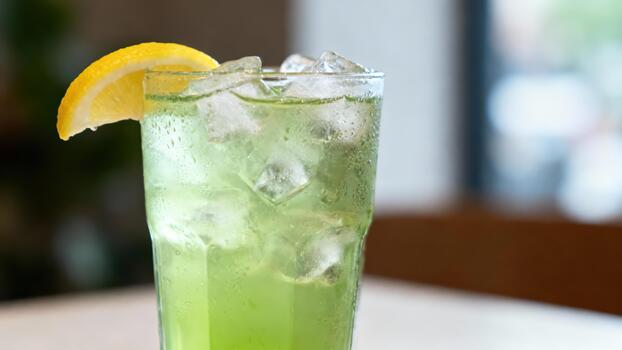 Refreshing tall glass filled with a chilled green beverage garnished with a citrus slice photo