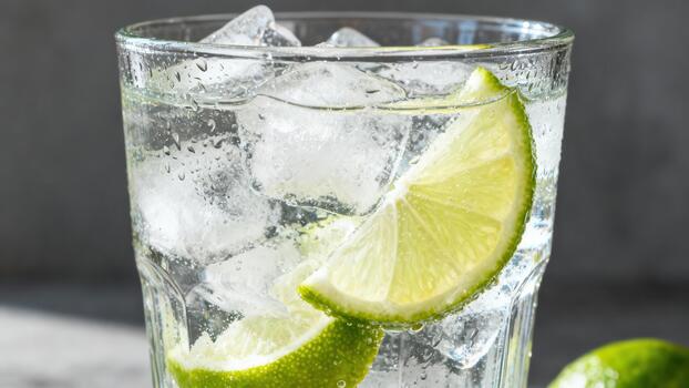 Refreshing clear beverage with ice cubes and bright citrus slices fills a textured drinking vessel photo