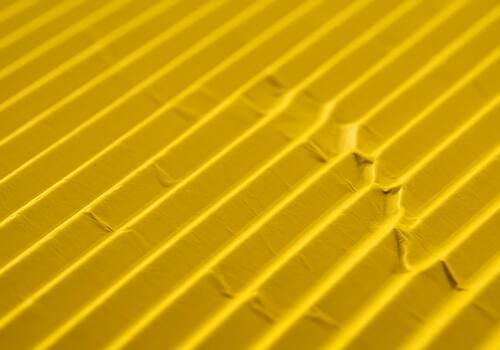 Close-up of a vibrant golden yellow patterned surface showcasing rhythmic diagonal lines and textured grooves creating an interesting abstract photo