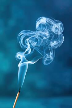 Soft incense smoke rising gracefully from a stick, creating ethereal patterns against a blurred blue background, evoking a sense of calm and tranquility with copy space photo