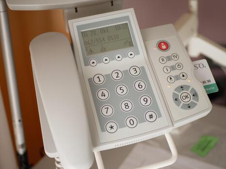 Close-up of modern hospital bedside communication device with numeric keypad, display, and control buttons for patient use in healthcare room photo