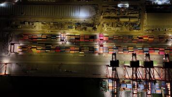 över huvudet natt se av mersin behållare terminal med ljust belyst brygga kranar läser in och avlastning en massiv fartyg, upptagen frakt gård och upplyst kaj operationer video