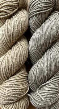 Close up view of two skeins of variegated yarn in earthy tones of beige and grey showcasing subtle color transitions and texture photo