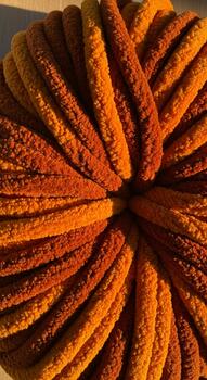 Close up view of a fuzzy textured yarn ball in warm shades of orange and brown creating a circular pattern photo