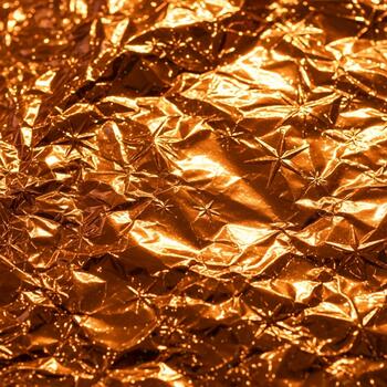 Close up textured abstract background of crumpled metallic gold foil reflecting light and creating intricate patterns photo