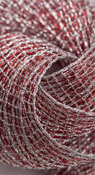 Close up macro view of a textured roll of metallic red and silver woven craft ribbon with shimmering threads photo