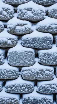 Stacked rectangular stones covered in a thick layer of soft white snow creating a textured winter landscape pattern photo