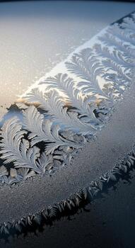 Abstract close up of intricate ice crystal patterns forming on a dark surface with soft light reflecting photo