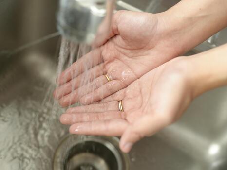 Washing hands under running water promotes hygiene and cleanliness. image captures close up of hands receiving water from faucet, emphasizing importance of handwashing photo