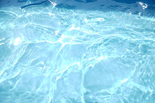 A serene, top-down view of shimmering blue water with sunlit ripples, creating a beautiful abstract pattern. The clear surface evokes feelings of calmness photo