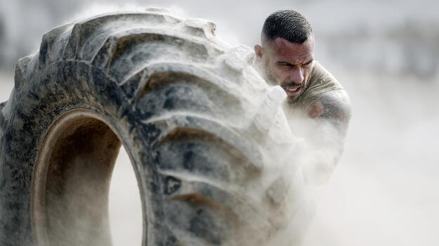 Man Flipping Large Tire In Intense Workout. Strength And Determination In Fitness Training photo