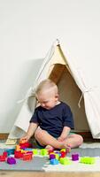 bambino piccolo ragazzo si siede a casa su un' tappeto e costruisce un' Torre a partire dal un' costruzione impostare. autosviluppo di un' bambino sviluppo di bene il motore abilità di mani nel bambini. bambino giochi con un' costruzione impostato video