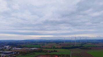spazzato dal vento i campi e torreggiante turbine allungare attraverso il orizzonte sotto un' lunatico cielo nel un' sereno campagna ambientazione video