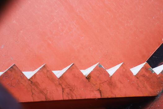 Closeup of a serrated red metal edge with sharp triangular points photo