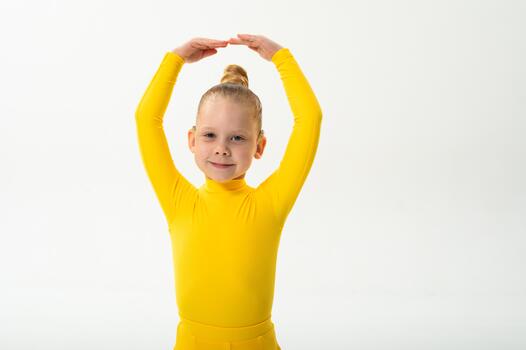 Smiling girl in bright yellow practicing choreography with hearing device. Confidence, concentration, and harmony of movement despite deafness, showing inclusion and technological progress in photo