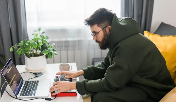 Guy music producer or arranger using laptop and midi keyboard and other audio equipment to create music at home studio. Beat making and arranging audio content and composing song concept. photo