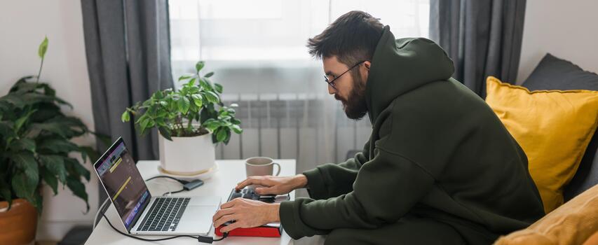 Banner Man music producer or arranger using laptop and midi keyboard and other audio equipment to create music at home studio. Beat making and arranging audio content and composing song concept photo