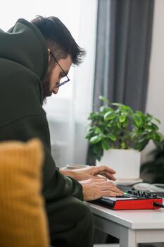 Man recording electronic music track with portable midi keyboard on laptop computer in home studio close-up. Producing and mixing music beat making and arranging audio photo