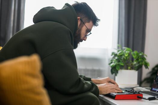 Man music producer or arranger using laptop and midi keyboard and other audio equipment to create music at home studio. Beat making and arranging audio content and composing songs photo