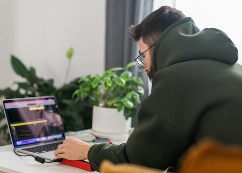 hombre música productor o arreglista utilizando ordenador portátil y midi teclado y otro audio equipo a crear música a hogar estudio. golpear haciendo y arreglando audio contenido. foto