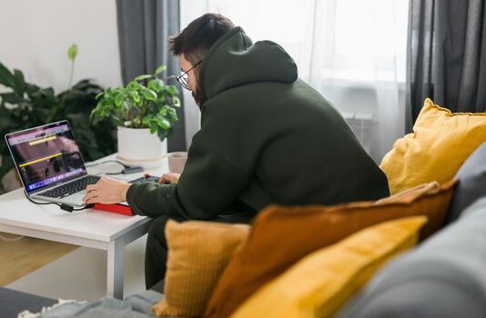 Man music producer or arranger using laptop and midi keyboard and other audio equipment to create music at home studio. Beat making and arranging audio content and composing songs. photo