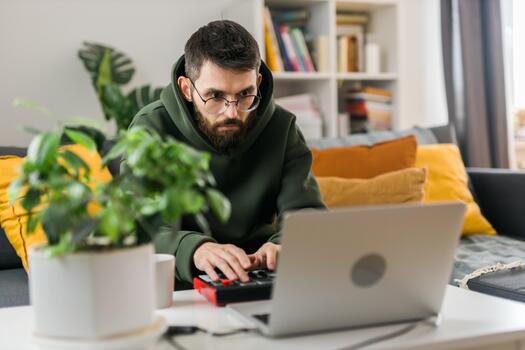 Man music producer or arranger using laptop and midi keyboard and other audio equipment to create music at home studio. Beat making and arranging audio. photo