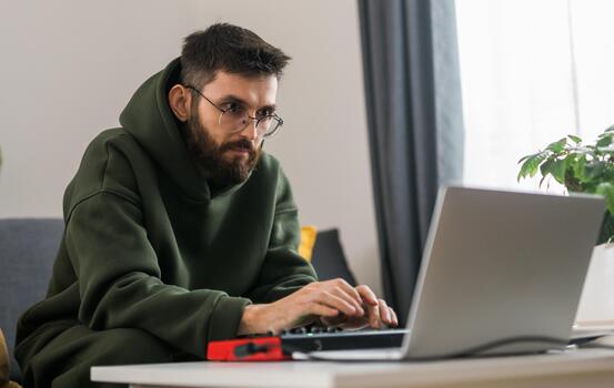 Male music producer or arranger using laptop and midi keyboard and other audio equipment to create music at home studio. Beat making and arranging audio content and composing song concept photo