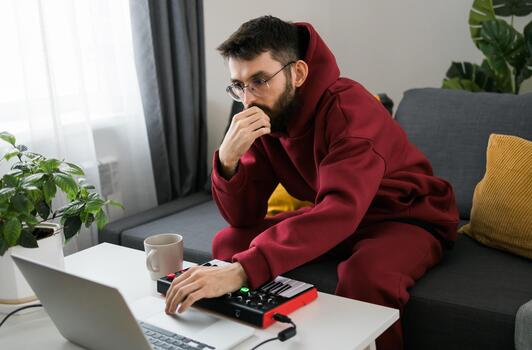 hombre música productor o arreglista utilizando ordenador portátil y midi teclado y otro audio equipo a crear música a hogar estudio. golpear haciendo y arreglando audio contenido y composición canción concepto. foto