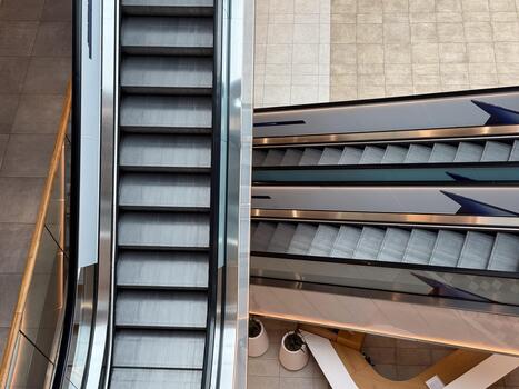 Escalators inside a contemporary shopping center viewed from above. Movement, symmetry, and urban architecture symbolizing daily routine and structure. photo