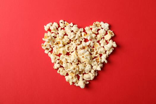 Flat lay composition with popcorn heart on red background, space for text photo