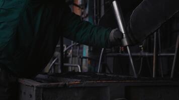 de bearbeta av framställning stål förbi som man introducerar sand in i formar och pressar. fabrik arbetare använder sig av konstruktion verktyg medan arbetssätt. video