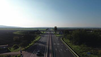 View of a busy intersection on an expressway with various cars and trucks navigating multiple exits. Lush greenery and mountains are visible in the background on a clear day. video