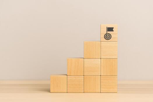 Wooden blocks stacked in step formation with target and flag symbol on top block representing 2026 planning roadmap for goal achievement and strategic success in clear concept photo