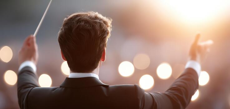 Skilled conductor leads orchestra with passion and precision, guiding musicians through captivating performance under warm sunset glow photo
