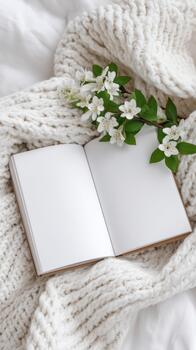 Cozy scene featuring open blank book resting on soft knitted blanket with delicate white flowers nearby, symbolizing mental health and wellness through creativity and reflection photo