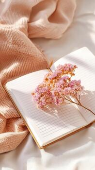 Cozy scene featuring soft pink sweater, open notebook, and delicate pink flowers resting on pages creates serene atmosphere that promotes mental health and wellness photo