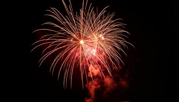A continuous shower of golden sparks and rich red light emanating from multiple synchronized bursts photo