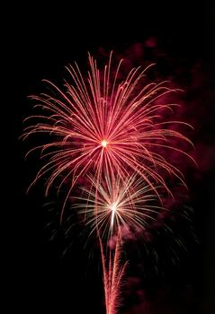 The intense pink and crimson glow of an exploding shell creating a luminous shower of light photo