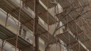 An empty construction site features scaffolding around a block of flats. Workers are preparing the building for insulation and renovation to enhance thermal efficiency. video