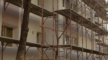 An empty construction site showcases scaffolding around a block of flats undergoing rehabilitation. Insulation work enhances the thermal efficiency of the structure. video