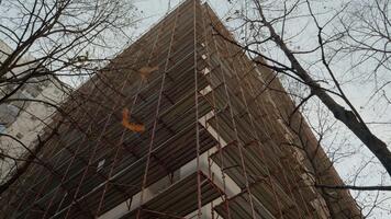 konstruktion arbetare är montera byggnadsställningar på ett lägenhet byggnad till förbereda för blockera isolering. detta projekt fokuserar på förstärkning termisk effektivitet och rehabilitering. video