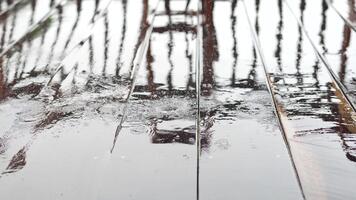 regn droppar skapande krusningar på trä- yta med reflexion och texturer, fångande stillhet och lugn av natur i en minimalistisk stil video