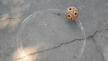 Colorful marble rolling on a textured surface creating circular patterns of art and design under warm sunlight video