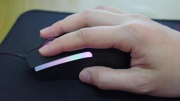 en hand interagera med en elegant dator mus terar vibrerande led lampor, uppsättning mot en svart mus vaddera, visa upp modern teknologi och ergonomisk design för produktivitet. video