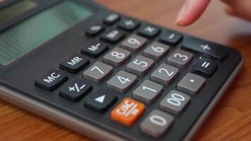 A close-up image of a calculator resting on a wooden table showcases its buttons and display, highlighting its utility for financial calculations and office tasks. video