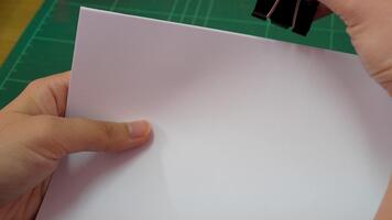 uma fechar-se imagem do uma mão segurando uma em branco Folha do papel contra uma brilhante verde corte esteira. ideal para representando criatividade e Projeto projetos, enfatizando uma limpar \ limpo área de trabalho. video