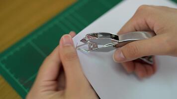 en närbild se av en hand införing en papper klämma in i en stack av vit papper på en grön skärande matta, symboliserar organisation och produktivitet i en arbetsyta. video