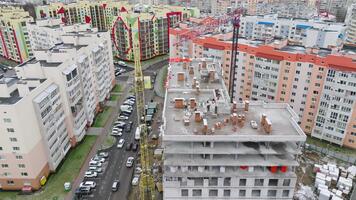 New block of flats being constructed in the area. Slow approach to the construction site on the roof of the building with people working at it. video