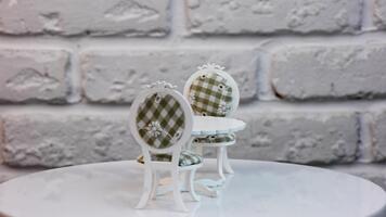 leksak möbel uppsättning som innehåller en tabell och två stolar. vit ett ben tabell och stolar med färgad hölje på de roterande stå. stänga upp. video
